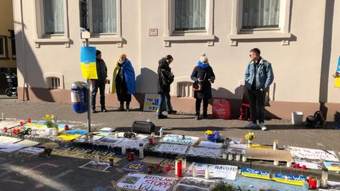 Bilder, Plakate, Blumen und Kerzen auf der Straße in blau-gelb.