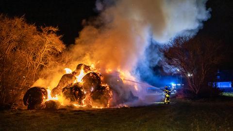 Ein Feuerwehrmann löscht brennende Strohballen