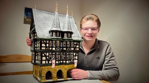 Ein junger Mann präsentiert stolz das Modell des historischen Rathaus Alsfeld, welches er selber gebastelt hat.