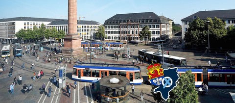 Blick von oben auf einen städtischen Platz mit Straßenbahnen, Bussen und vielen Menschen. Auf dem Bild eine kleine Grafik mit einer blau eingefärbten Fläche (Umriss der Stadt), dem Wappen der Stadt Darmstadt und einem Wahlkreuz.