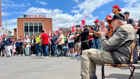 Viele Menschen demostrieren stehend und sitzend vor dem Goodyear-Fulda Fabrikgebäude