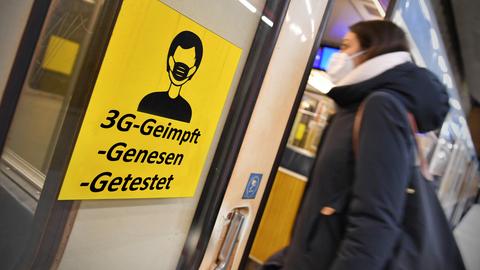Frau mit Maske steigt in eine Bahn, an deren Tür ein großes gelbes Schild mit "3G-geimpft, getestet, genesen" klebt.