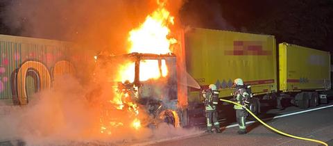 Feuerwehrleute löschen einen brennenden Lastwagen auf der A3 bei Niedernhausen.