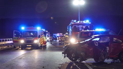 Unfallstelle auf der A45 bei Florstadt - im Vordergrund steht ein roter Pkw, stark beschädigt. Im Hintergrund Rettungskräfte im Einsatz. 