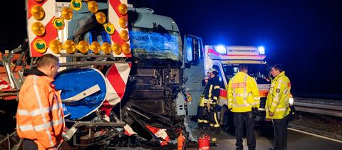 Unfall-Lkw in demolierter Baustelle auf der Autobahn 60, Einsatzkräfte stehen daneben, es ist Nacht