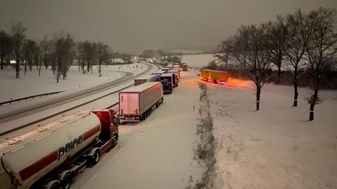 Mehrere Lkw stehen auf schneebedeckter Straße