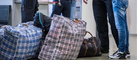 Ein Mann steht vor seiner Abschiebung mit Gepäck am Flughafen. (Symbolbild)