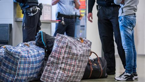 Ein Mann steht vor seiner Abschiebung mit Gepäck am Flughafen. (Symbolbild)