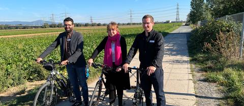 ADFC-Landesgeschäftsführer Sofrony Riedmann, stellvertretende Landesvorsitzende Helga Hofmann und Landesvorsitzender Ansgar Hegerfeld mit Fahrrädern an einem Feld.