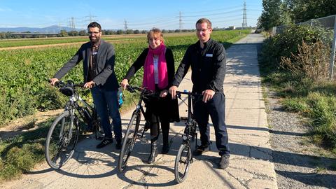 ADFC-Landesgeschäftsführer Sofrony Riedmann, stellvertretende Landesvorsitzende Helga Hofmann und Landesvorsitzender Ansgar Hegerfeld mit Fahrrädern an einem Feld.