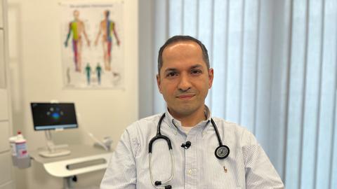 Arzt Mehran-Yaschar Adili sitzt in einem Behandlungszimmer