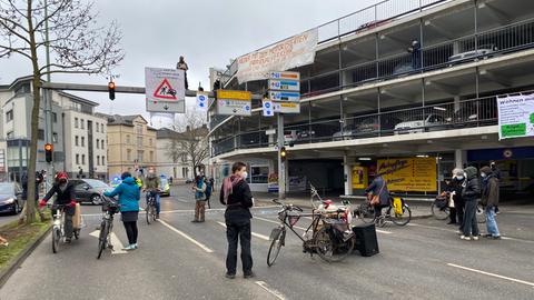 Aktivisten stehen mit Fahrrädern auf der Straße, einer ist auf eine Ampel geklettert.