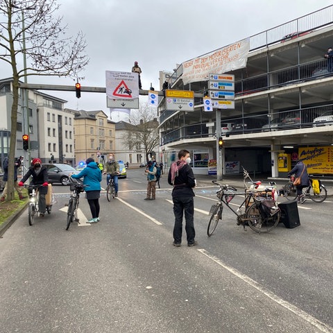 Aktivisten stehen mit Fahrrädern auf der Straße, einer ist auf eine Ampel geklettert.