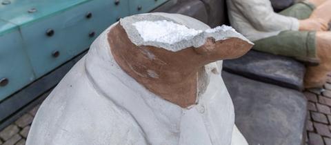 Das Bild zeigt eine Skulptur aus Beton, der der Kopf abgeschlagen wurde. 