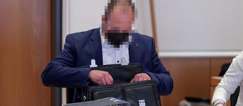 Ein Mann im Anzug sitzt an einem Tisch und legt Dokumente in eine Aktentasche