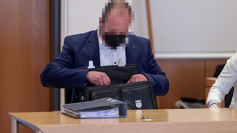 Ein Mann im Anzug sitzt an einem Tisch und legt Dokumente in eine Aktentasche