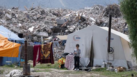 Der neunjährige Yakup steht am Stadtrand von Antakya vor seinem Zelt, in dem er seit dem Erdbeben lebt.