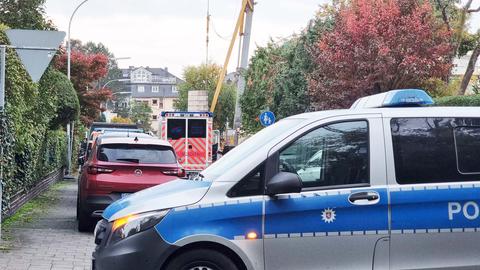 Foto: Blick in eine Straße, die von einem Polizeiwagen (im Vordergrund) abgesperrt ist. In der Straße steht ein Rettungswagen, daneben Kran und Baustelle.