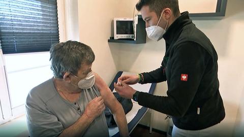 Ein Arzt klebt einem Patienten ein Pflaster auf den Arm.