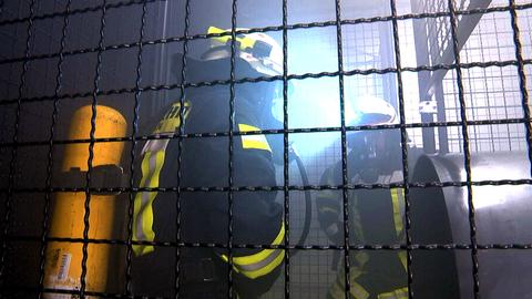 Zwei Feuerwehrmänner stehen in voller Montur in dem Drahtkäfig der Teststrecke in Schwalmstadt.