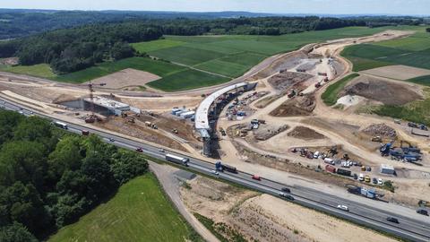 Die Baustelle der Autobahn 49 am Ohmtaldreieck: Zu sehen ist eine Autobahn, neben der gebaut wird. Eine halbfertige Brücke führt zu dieser Autobahn.