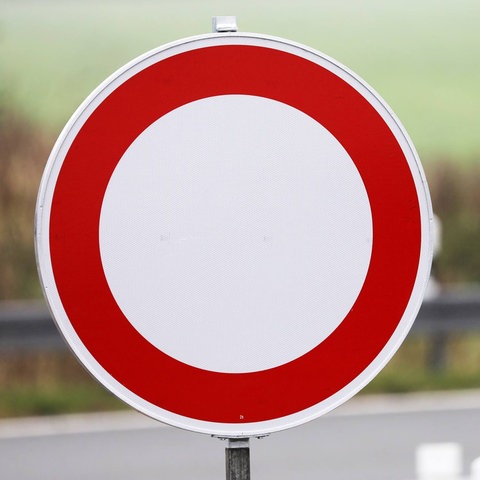 Verkehrsschilder in Großaufnahme: "Durchfahrt verboten" im scharf Bildvordergrund und "Autobahn" unscharf im Bildhintergrund.