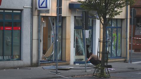 Ein Ermittler kniet vor den zerborstenen Scheiben der Filiale der Deutschen Bank in Neu-Isenburg.