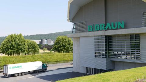 Blick auf eine Industriehalle mit der Aufschrift B.Braun. Daneben fährt auf einer Straße ein LKW mit der Aufschrift B.Braun. Im Hintergrund ist Landschaft zu sehen.