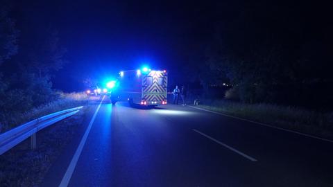 Rettungswagen mit Blaulicht auf einer Straße in der Nacht.