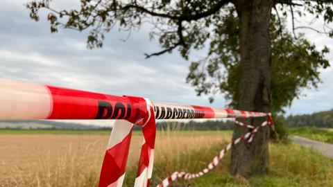 Wiese mit Polizeiabsperrung