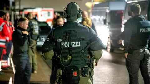 Mitarbeitende von Polizei (SEK) und Rettungsdienst stehen während eines Einsatzes in einer Straße.