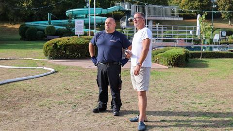 Sascha Schneider (l) von der Feuerwehr der Stadt Bad Schwalbach und Bademeister Richard van Rijn stehen am Becken zusammen.