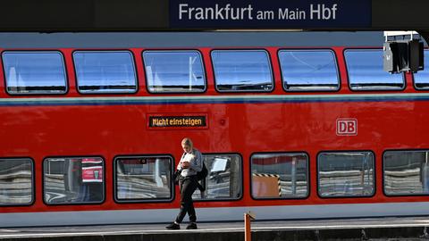 Eine Frau steht an einem Gleis des Frankfurter Hauptbahnhofs vor einem Regionalzug, auf dem die Anzeige "Nicht einsteigen" leuchtet. 