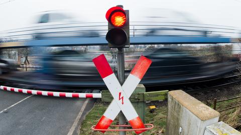 Beschrankter Bahnübergang mit vorbeifahrendem Zug