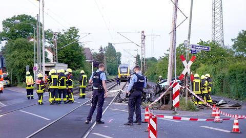 Polizisten und Rettungskräfte stehen am Bahnübergang in Frankfurt-Nied nach dem Unfall und dokumentieren das Geschehene.