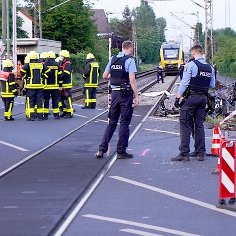 Polizisten und Rettungskräfte stehen am Bahnübergang in Frankfurt-Nied nach dem Unfall und dokumentieren das Geschehene.