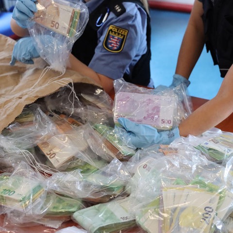 Polizisten schütten einen Sack mit Geld in Tüten auf einen Tisch