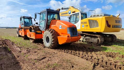 Zwei Baumaschinen stehen auf einem Feld.