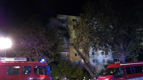 Feuerwehrwagen stehen vor einem Haus, aus dessen Fenstern dichter Rauch zeiht