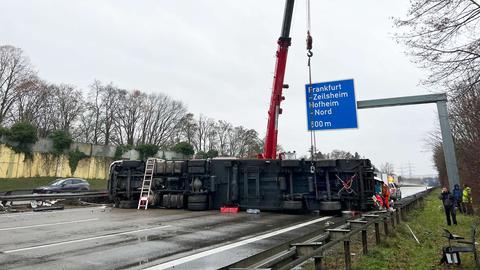 Auf der Fahrbahn liegt ein Lkw auf der Seite, der Boden des Lkw ist zu sehen. Dahinter ist ein Kran aufgestellt.