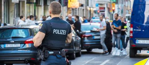 Polizist im Vordergrund, Flatterband und Autos und weiter Polizisten unscharf im Hintergrund