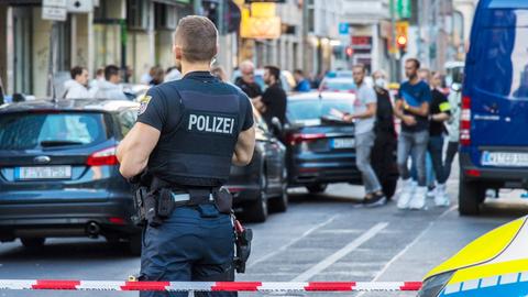 Polizist im Vordergrund, Flatterband und Autos und weiter Polizisten unscharf im Hintergrund