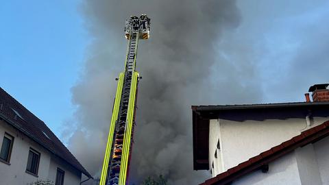 Aufsteigender Rauch hinter Haus, Feuerwehr mit Drehleiter