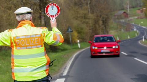 Ein Polizist gibt mit einer Kelle einem Autofahrer ein Signal zum Anhalten.