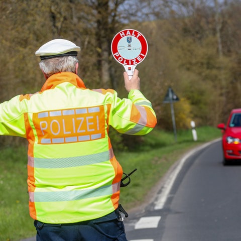 Ein Polizist gibt mit einer Kelle einem Autofahrer ein Signal zum Anhalten.
