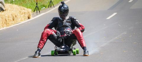 Ein fährt auf einem Bobbycar eine Straße hinunter.