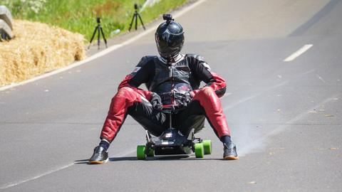 Ein fährt auf einem Bobbycar eine Straße hinunter.