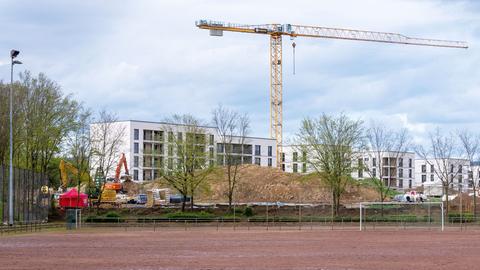 Foto einer Baustelle mit Kran, die hinter einem Fußballfeld liegt.