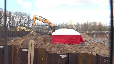 Ein Bagger und ein rotes Zelt inmitten eine umzäunten Baustelle.