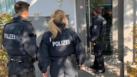 Polizisten stehen an einer Wohnungstür und klingeln.